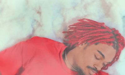 a man with red dreadlocks laying on a bed