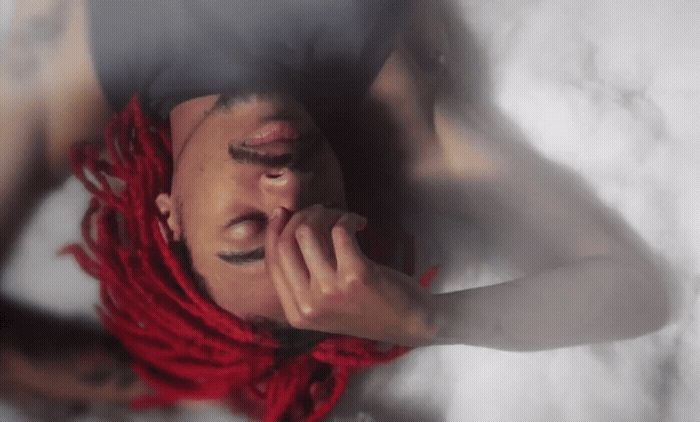 a man with red dreadlocks laying on a bed