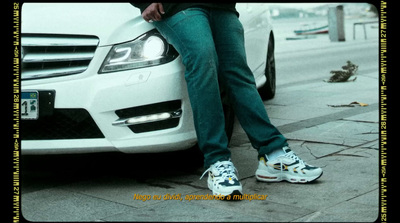 a person leaning against a white car on a sidewalk