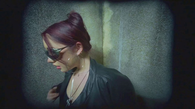 a woman with red hair and glasses standing in front of a wall