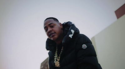 a man wearing a black jacket and a gold chain