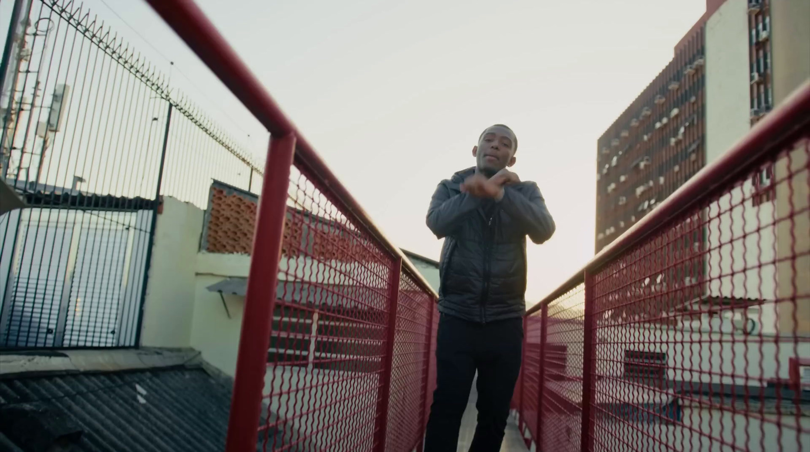 a man standing on a red fence next to tall buildings