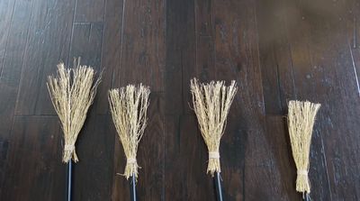 a group of three brooms sitting on top of a wooden floor