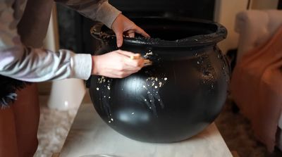 a person putting gold flakes in a large black pot