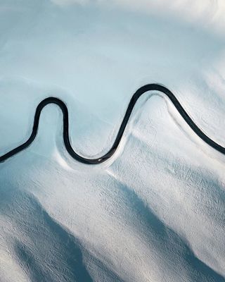 a winding road in the middle of a snow covered field