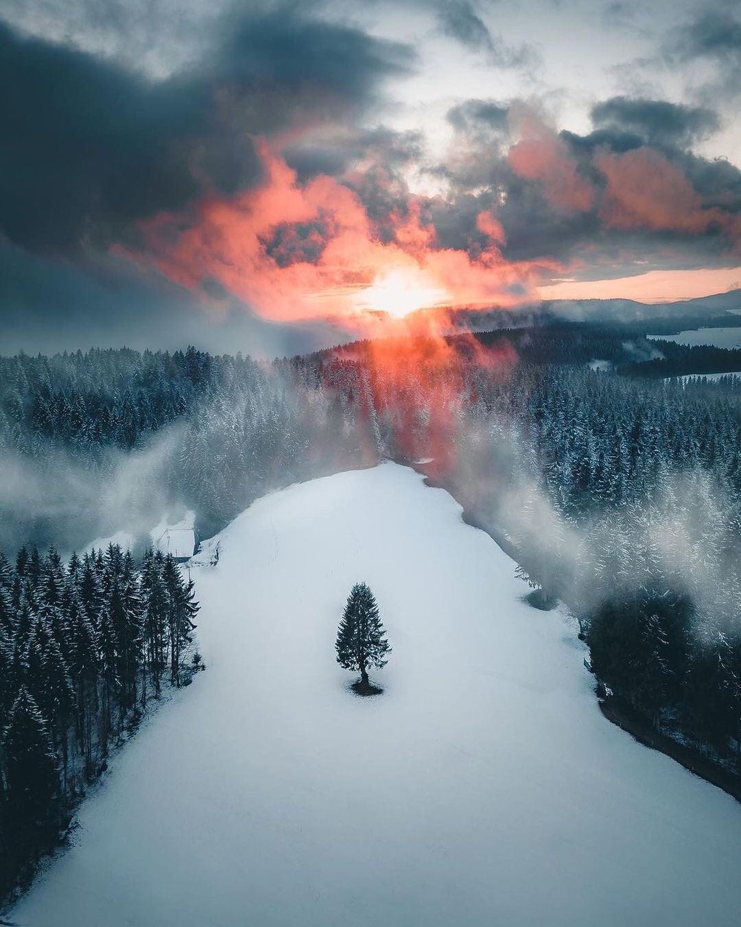 the sun is setting over a snowy landscape