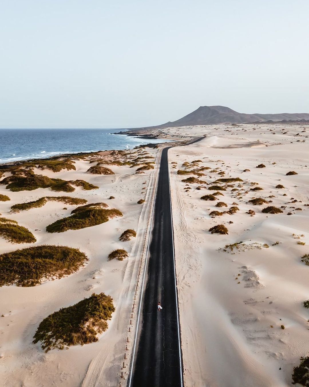 a car driving down a desert road next to the ocean