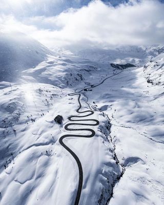 a winding road in the middle of a snow covered mountain