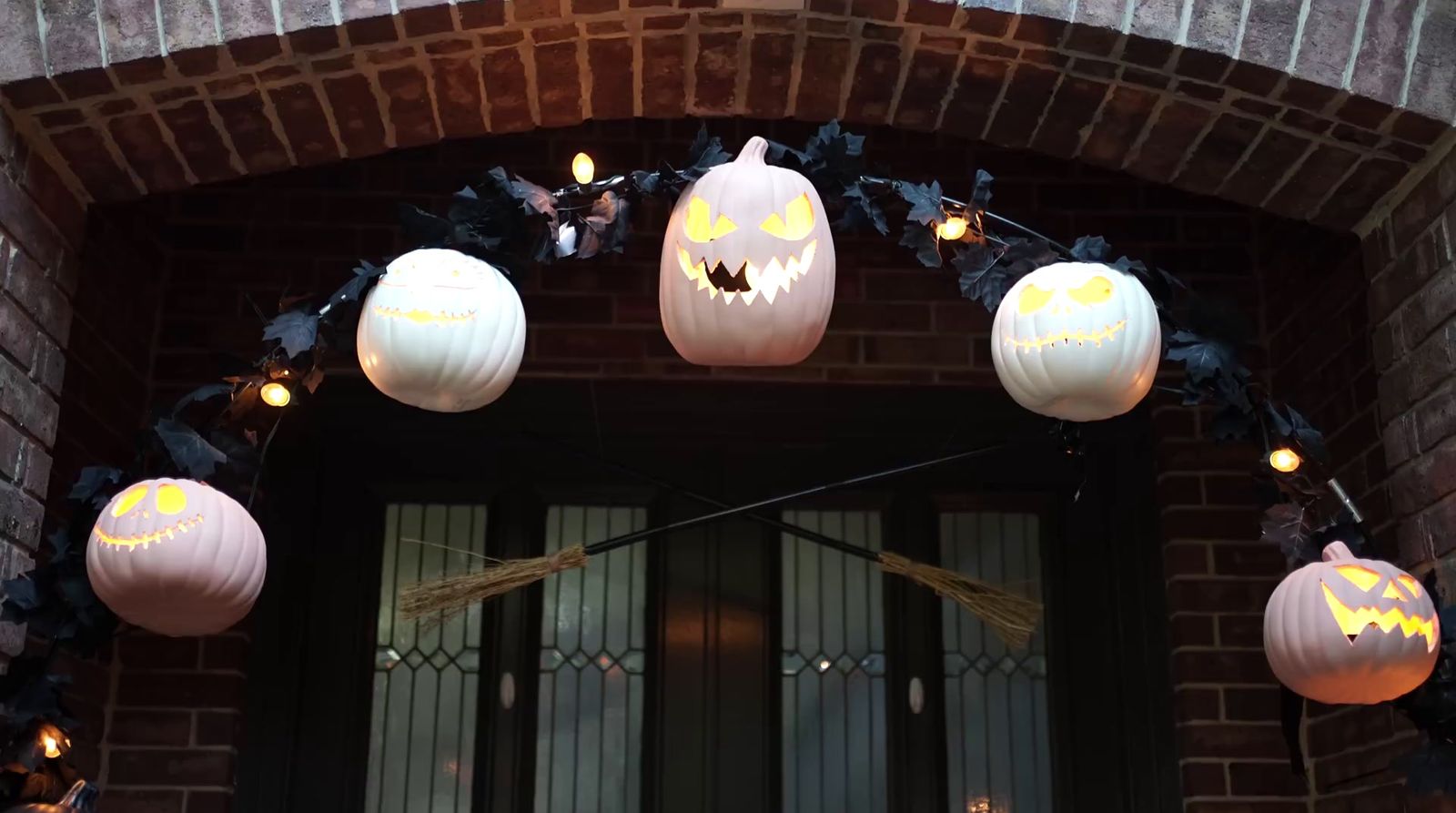 a front door decorated with pumpkins and lights