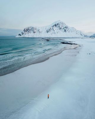 a person standing on a beach with mountains in the background