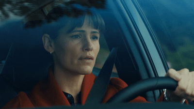 a woman driving a car with her hand on the steering wheel