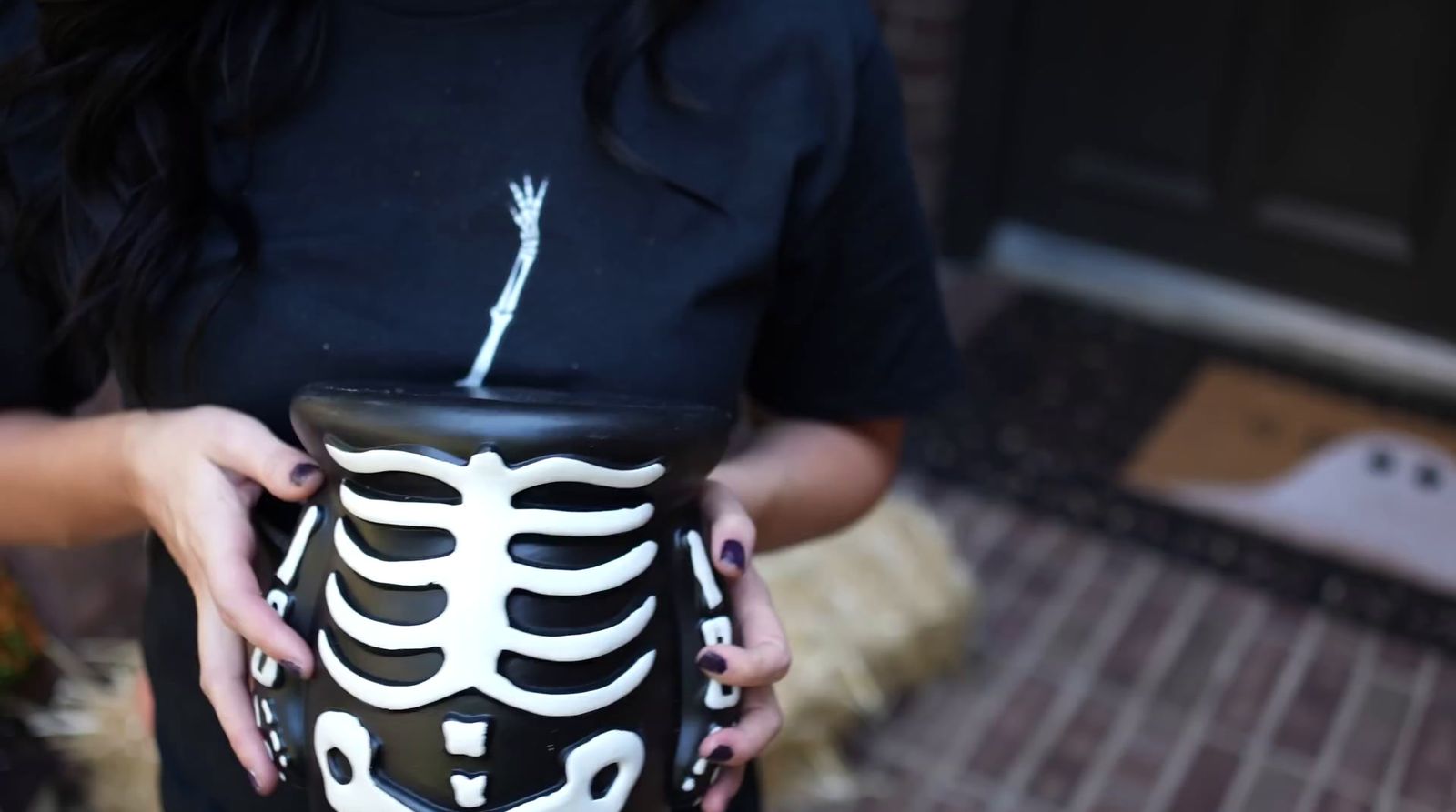 a woman holding a skeleton jar with a skeleton painted on it