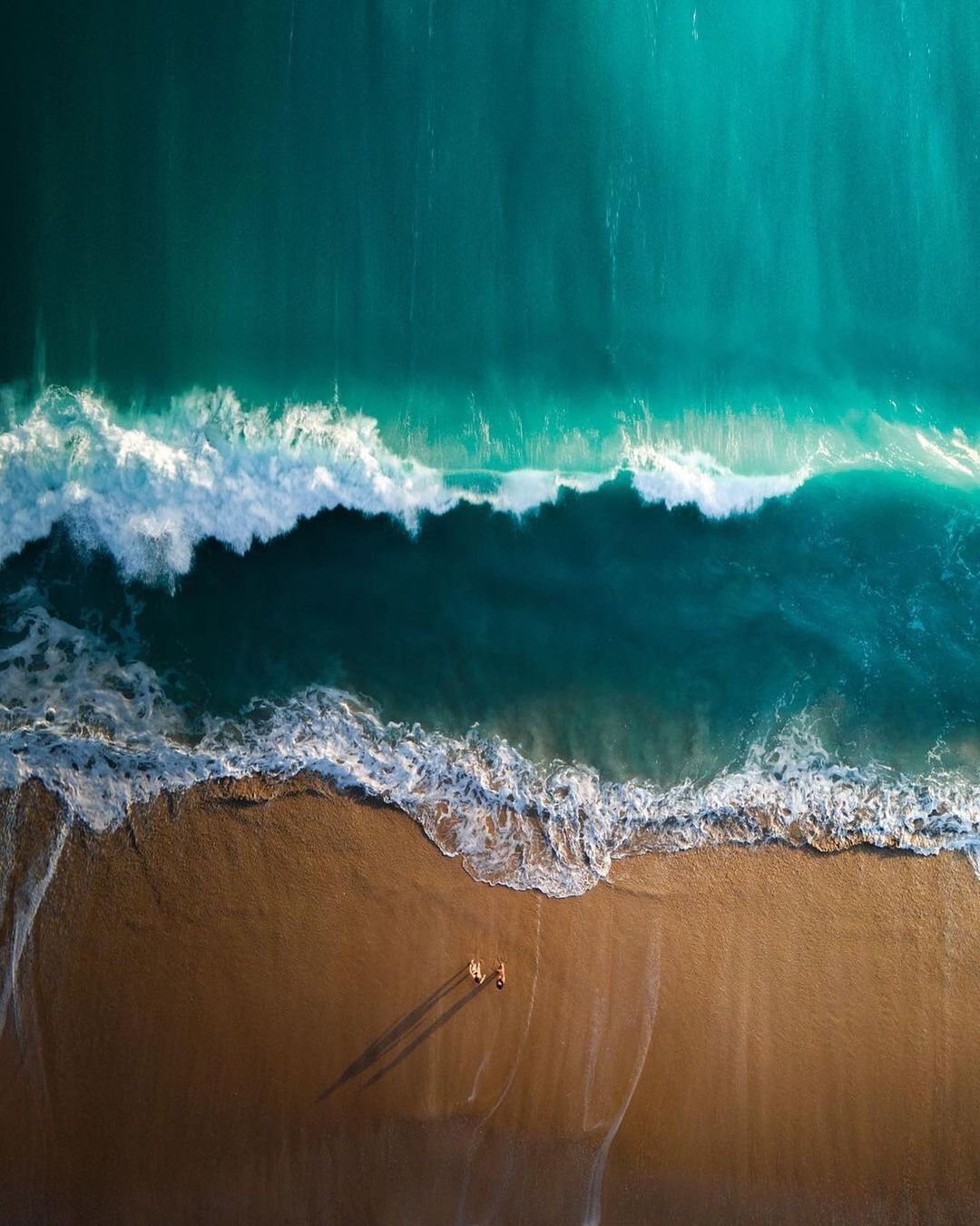 an aerial view of a beach with a boat in the water