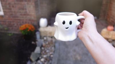 a person holding a coffee mug with a smiley face on it