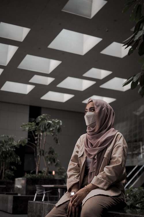 a woman wearing a face mask sitting on a bench