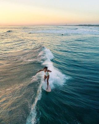 a woman riding a surfboard on a wave in the ocean