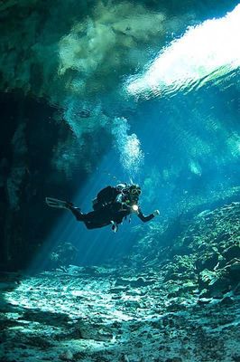 a person in a scuba suit swimming in a cave