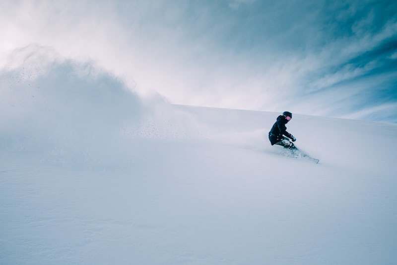 a man riding a snowboard down a snow covered slope