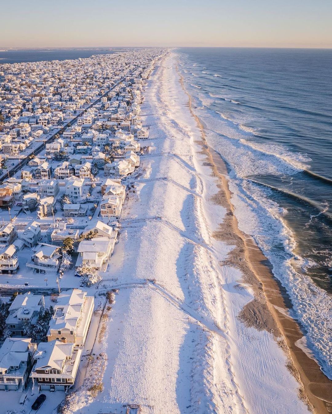 a beach covered in snow next to the ocean