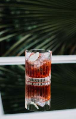 a glass with a drink inside of it sitting on a window sill