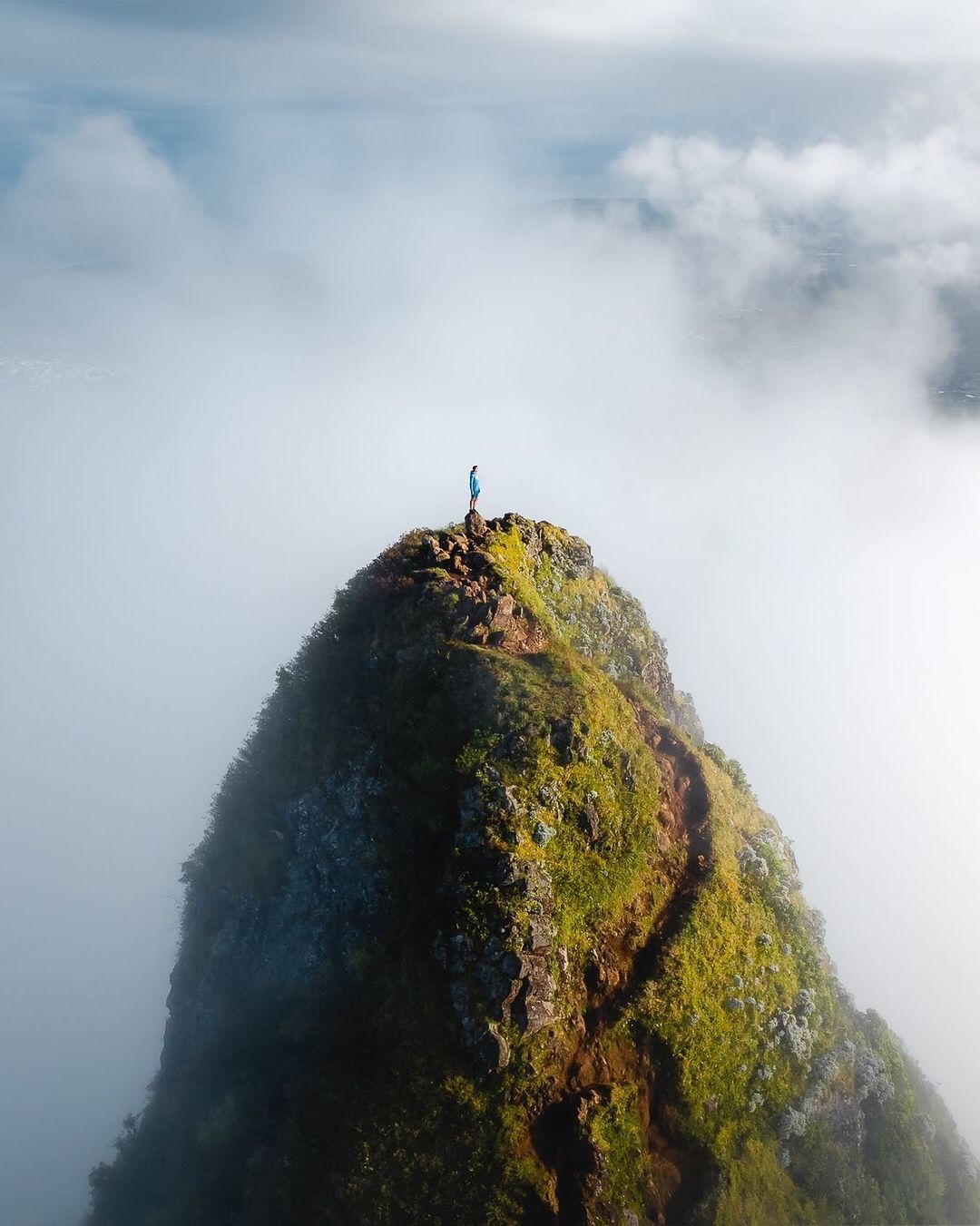 a person standing on top of a green mountain