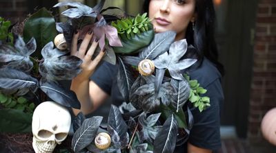 a woman holding a bunch of leaves and a skull