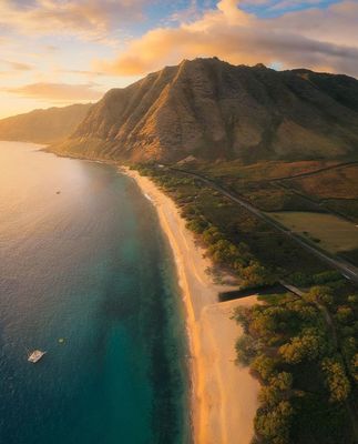 an aerial view of a beach with a mountain in the background