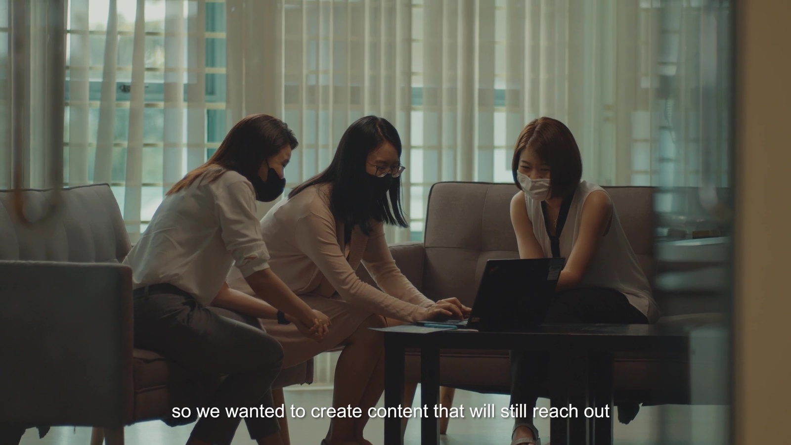 a group of people sitting around a table with laptops