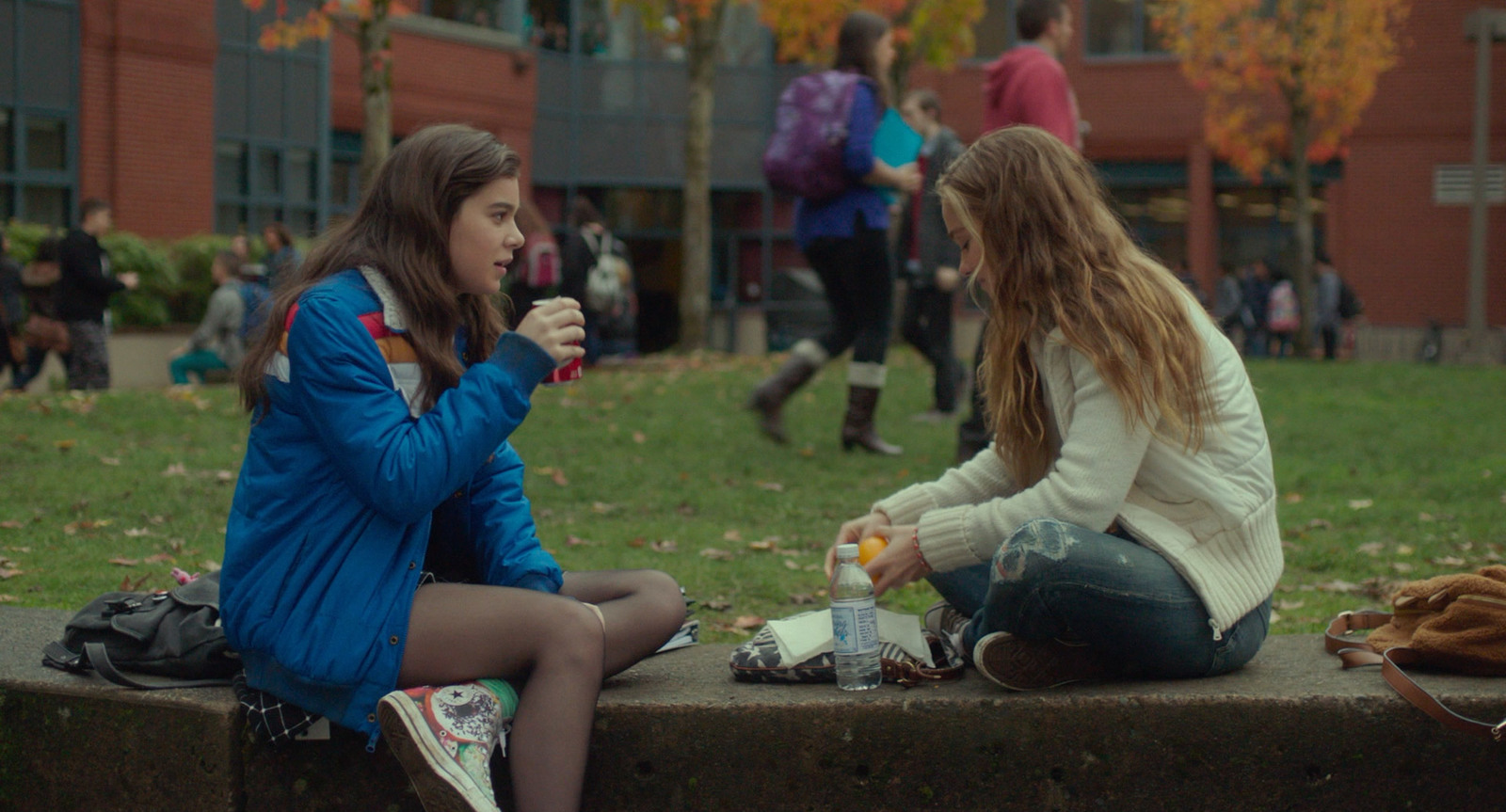 two girls sitting on a bench eating and drinking