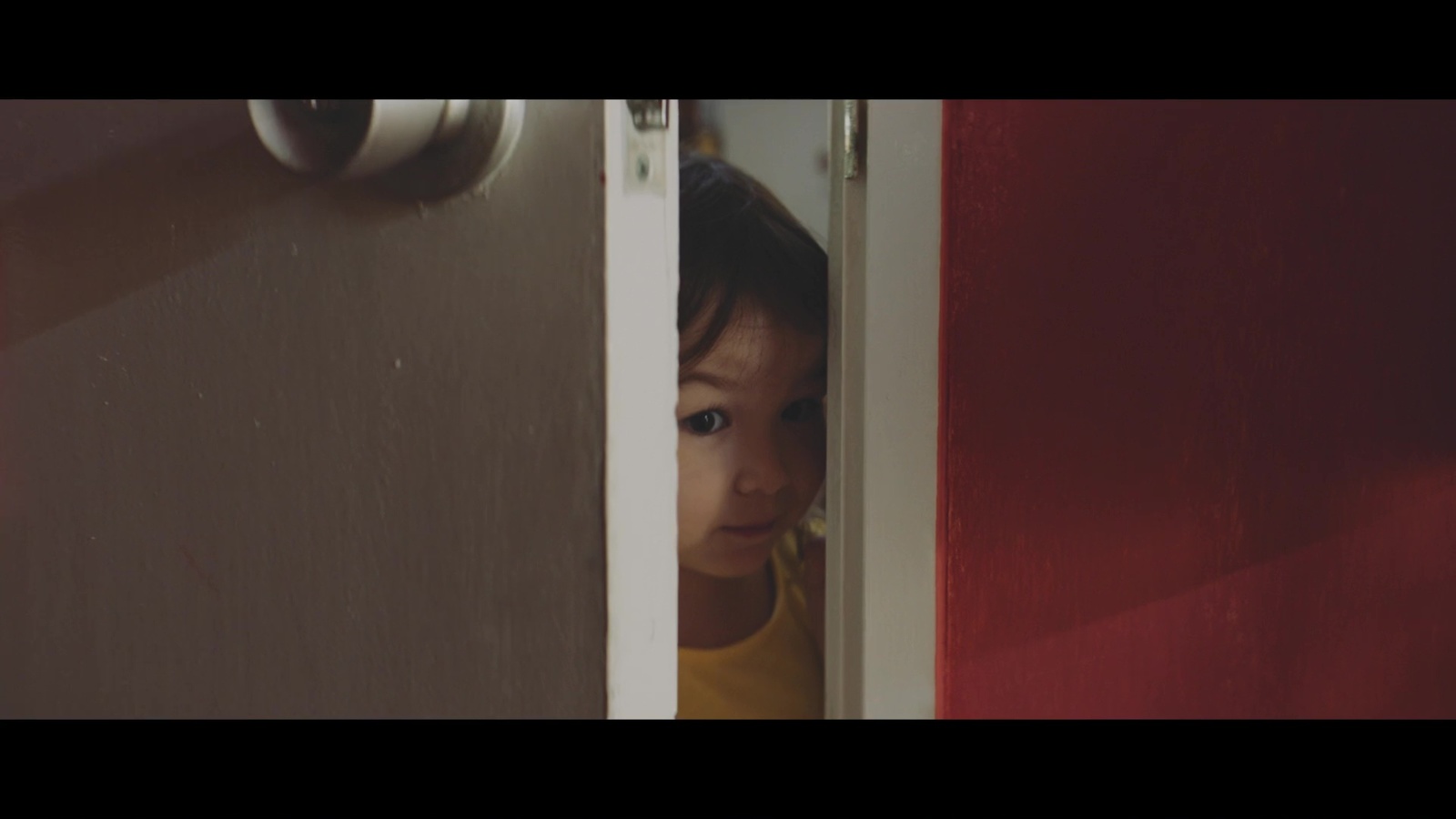 a little boy peeking out from behind a door