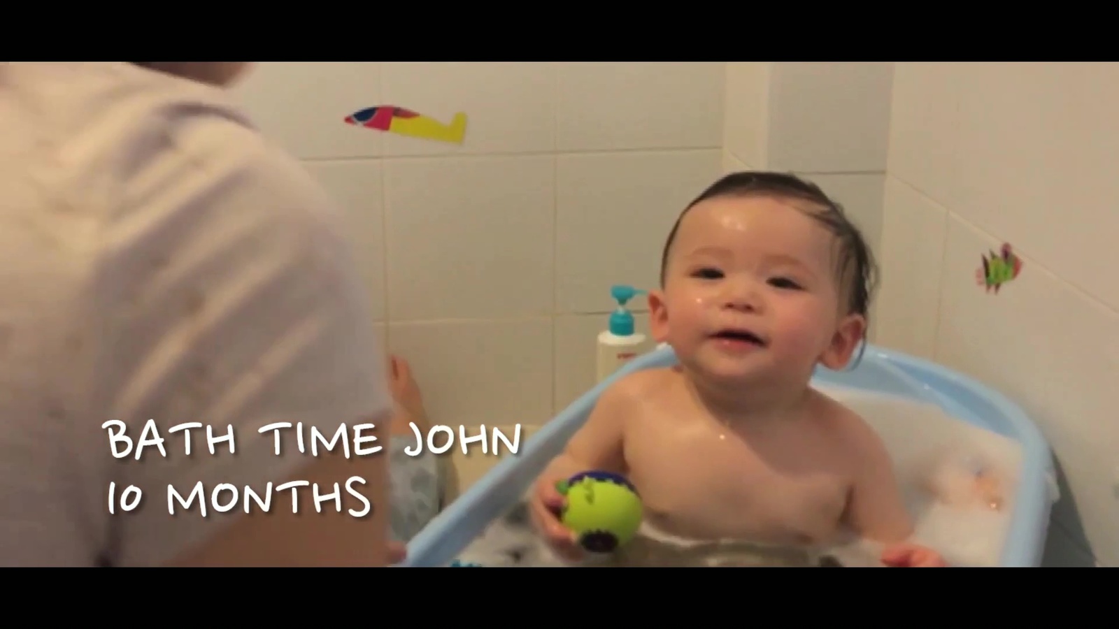 a baby sitting in a bath tub with a tennis ball in it