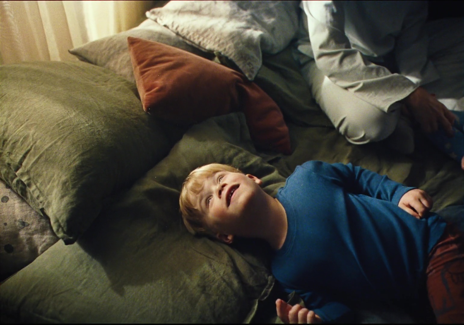 a young boy laying on a bed with pillows