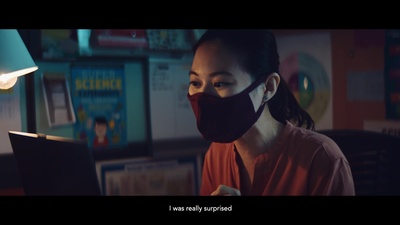 a woman wearing a face mask while looking at a laptop