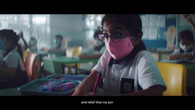 a young girl wearing a pink mask while sitting at a table