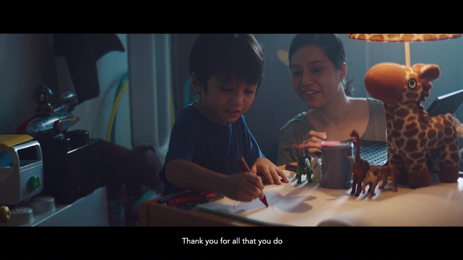 a woman and a boy are sitting at a table with a giraffe toy