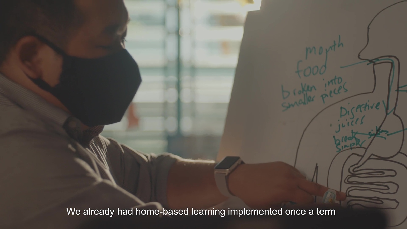 a man wearing a face mask writing on a whiteboard