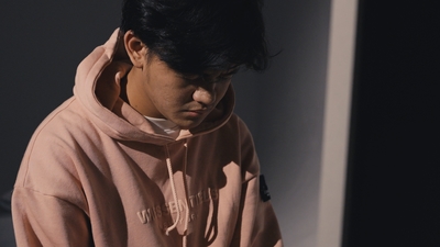 a man in a pink hoodie looking down at his cell phone