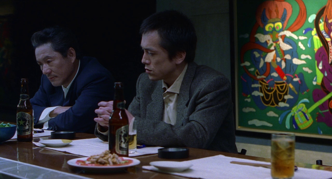 two men sitting at a table with plates of food