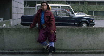 a man leaning against a wall on the side of a road