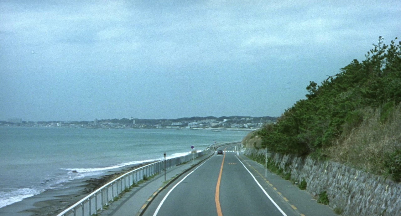 a car driving down a road next to the ocean