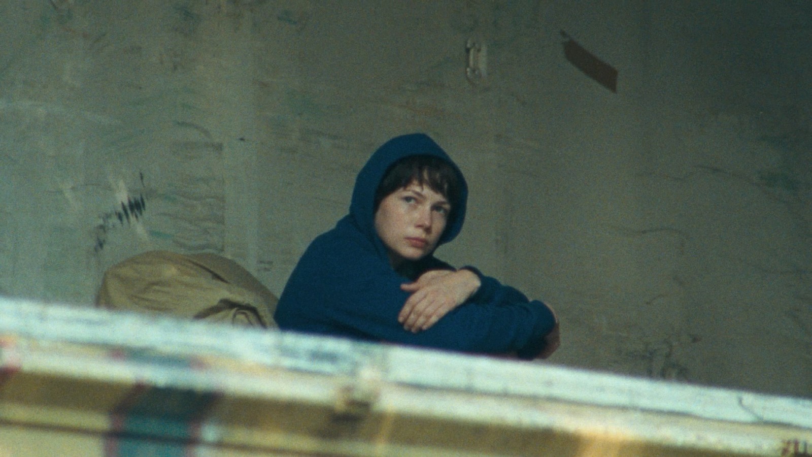 a woman in a blue hoodie sitting on a bed