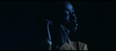 a woman in a dark room holding her hand up to her face