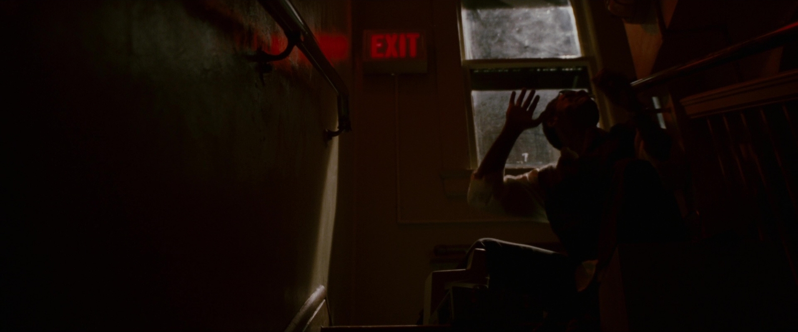 a person reaching up to a window in a dark room