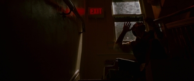 a person reaching up to a window in a dark room