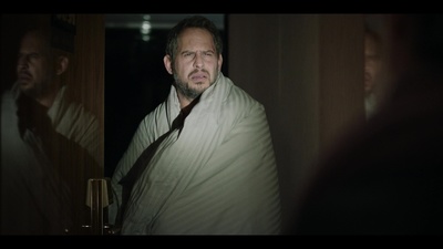 a man wrapped in a blanket standing in front of a mirror