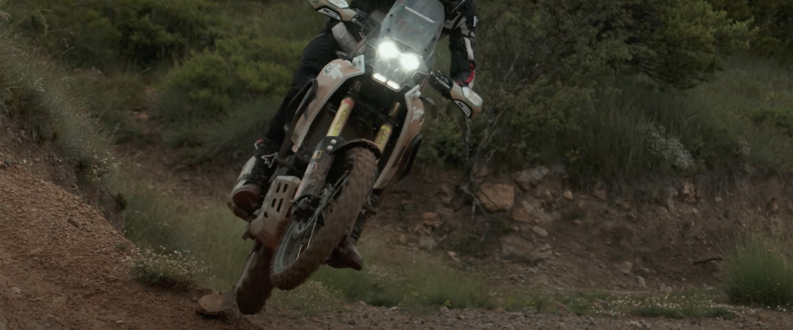 a man riding a motorcycle down a dirt road