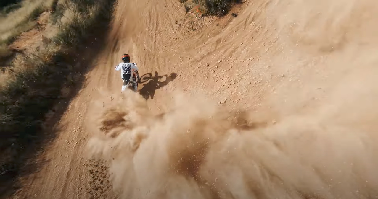 a man riding a dirt bike down a dirt road