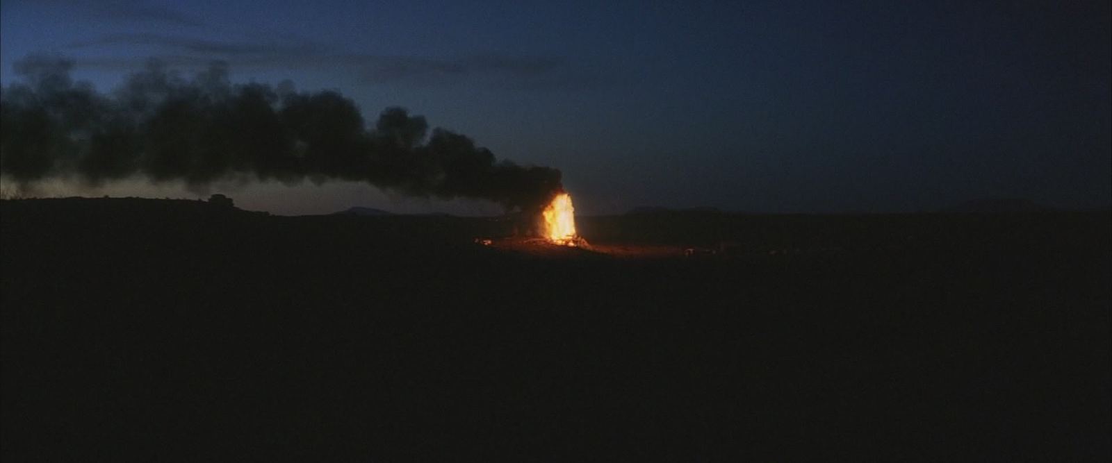 a group of smokestacks emitting from a dark sky