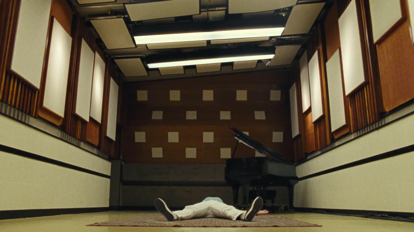 a person laying on the floor in front of a piano