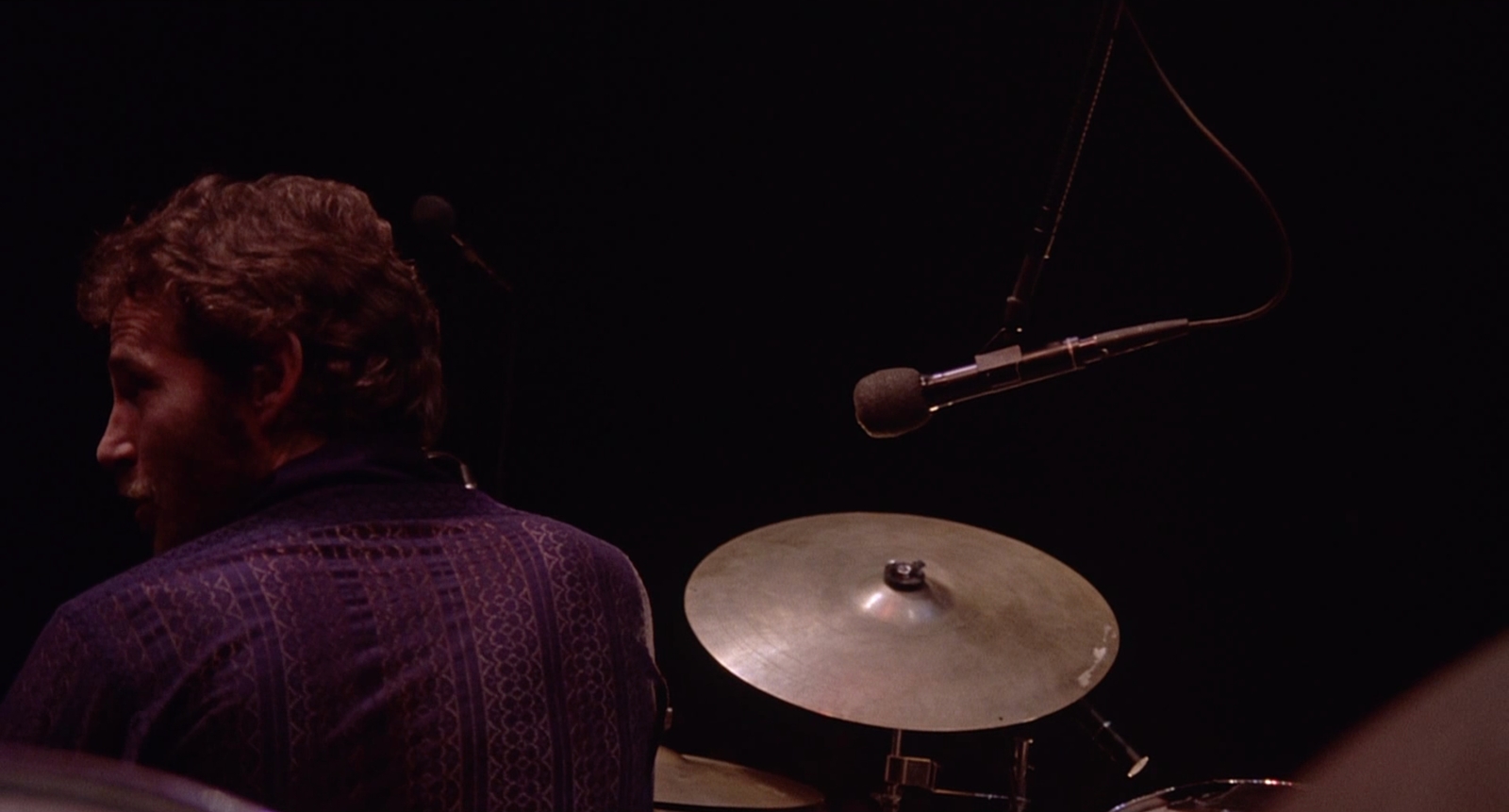 a man playing drums in front of a microphone